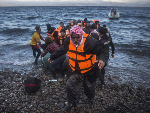 CRISE MIGRATÓRIA Iraquiano desembarca de um bote após cruzar o mar da costa da Turquia até uma praia de Lesbos, ilha da Grécia, com outros refugiados e migrantes. Milhares de pessoas seguem chegando à Europa, em fuga dos conflitos no oriente Médio (Foto: Santo Palacios/AP