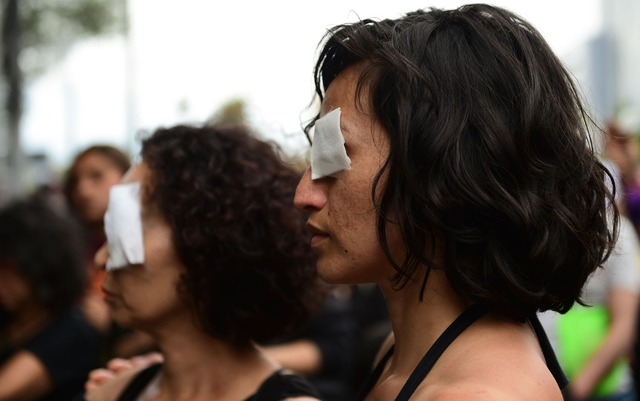 Mulheres vestidas de preto e usando curativos nos olhos participam de protesto em solidariedade aos manifestantes que sofreram ferimentos nos olhos, em Santiago, no Chile, na sexta-feira (1º) — Foto: Martin Bernetti/AFP