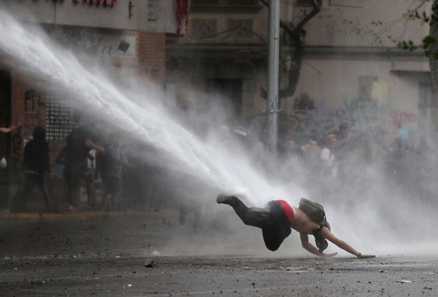 Manifestante é atingido por canhão d'água durante protesto contra o governo do Chile em Santiago na segunda-feira (11) — Foto: Ivan Alvarado/ Reuters
